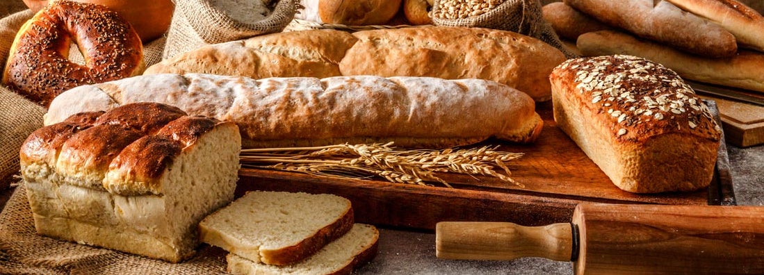 Different types of bread and rolling pin shot on rustic wooden table. Find Bakery Insurance.