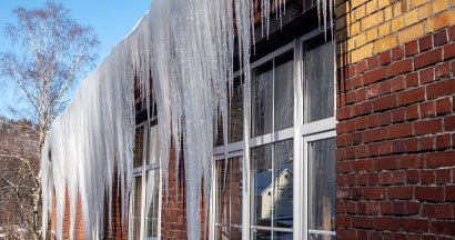 Huge icicles hang from the roof. How to Prevent Ice Dams and Who Pays for the Damage They Cause in Massachusetts.