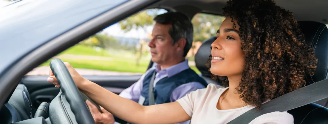 Driving instructor teaching woman to drive. Driver's Ed: Worth It or a Waste?