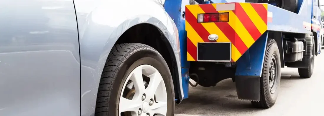 Tow truck towing a broken down car on the street. Find Salvage Title Insurance.