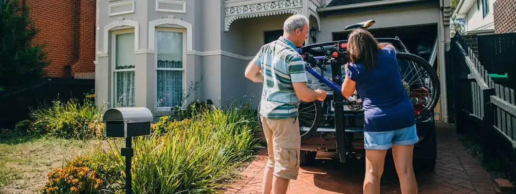 Middle aged couple in driveway attaching the family bikes to the bicycle rack on their car. Find Florida personal umbrella insurance.