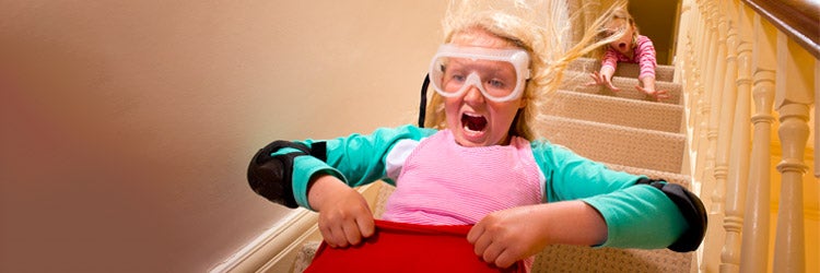 daredevil child comes down the stairs in a sleeping bag toboggan pushed by sister