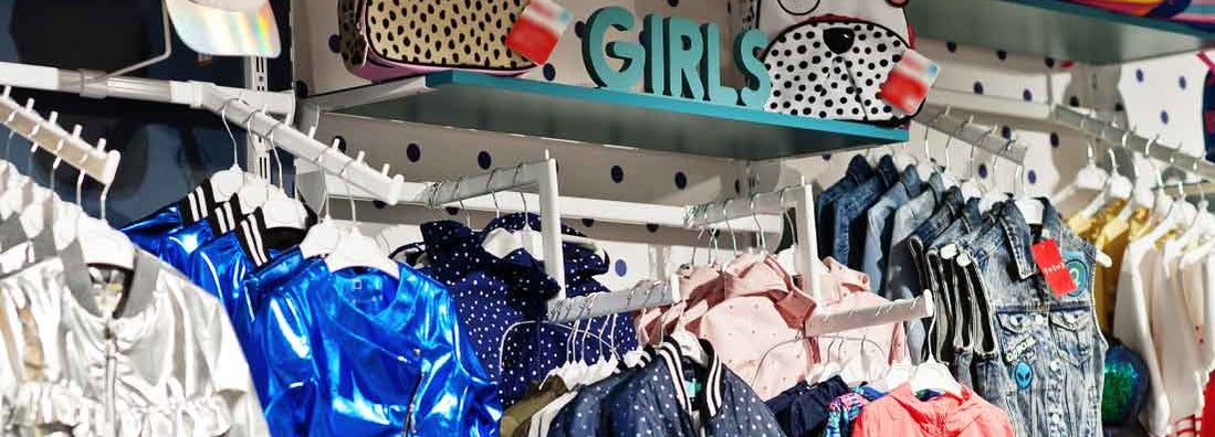 Children's bright clothes hang on the display in the baby clothing store