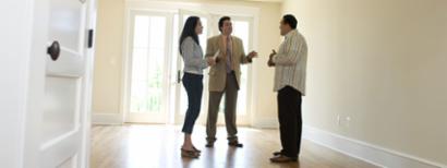 A realtor chats with potential homebuyers in an empty house.