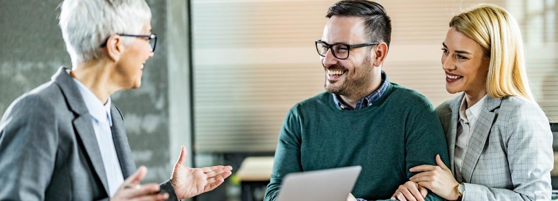 Happy couple talking to their insurance agent in the office. Your free guide to all the insurance that matters.