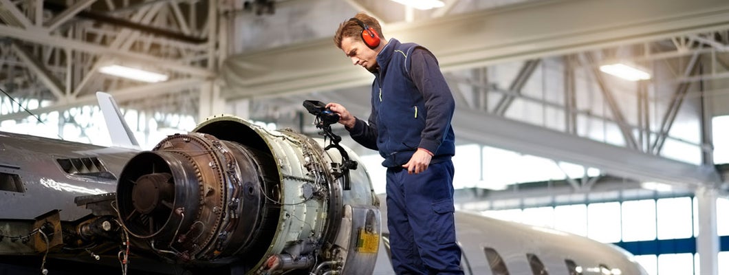 Aircraft engineer in the hangar repairing and maintaining airplane jet engine.