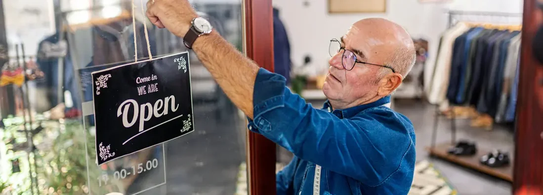Professional tailor putting an open sign on tailoring store door. Find Laramie, Wyoming business insurance.