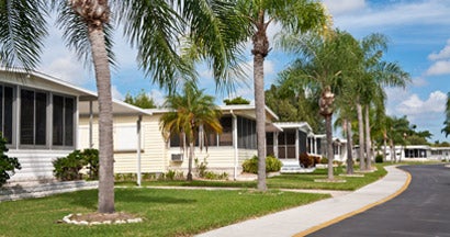 Mobile home park with palm trees and sidewalk. Find Mobile Home Insurance Cost.