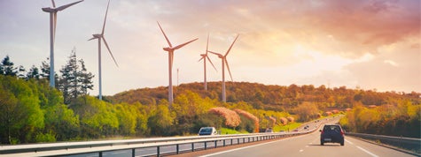 Cars going on highway in the landscape with wind propellers