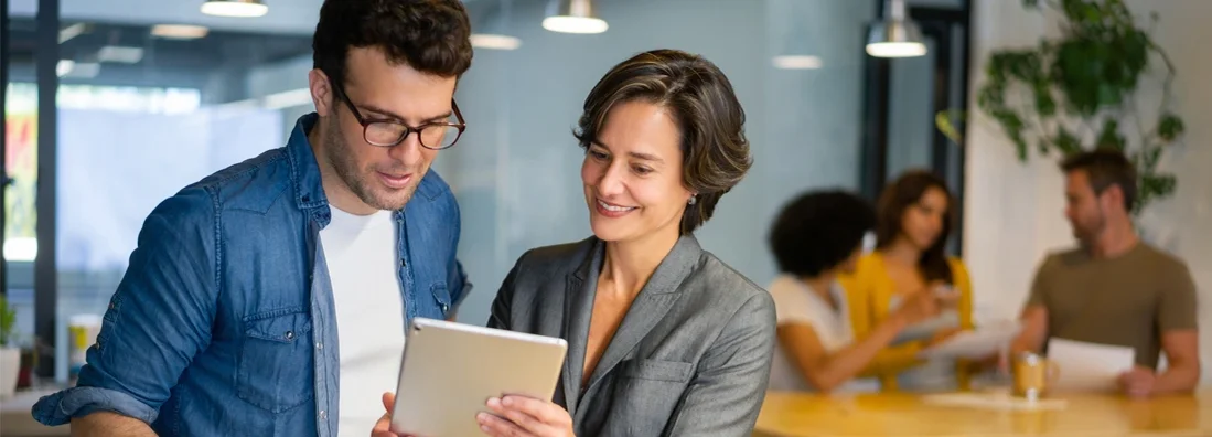 Coworkers working together at the office looking at documents on a tablet. Experts break down Herndon, VA business insurance costs, coverage, companies, and more.
