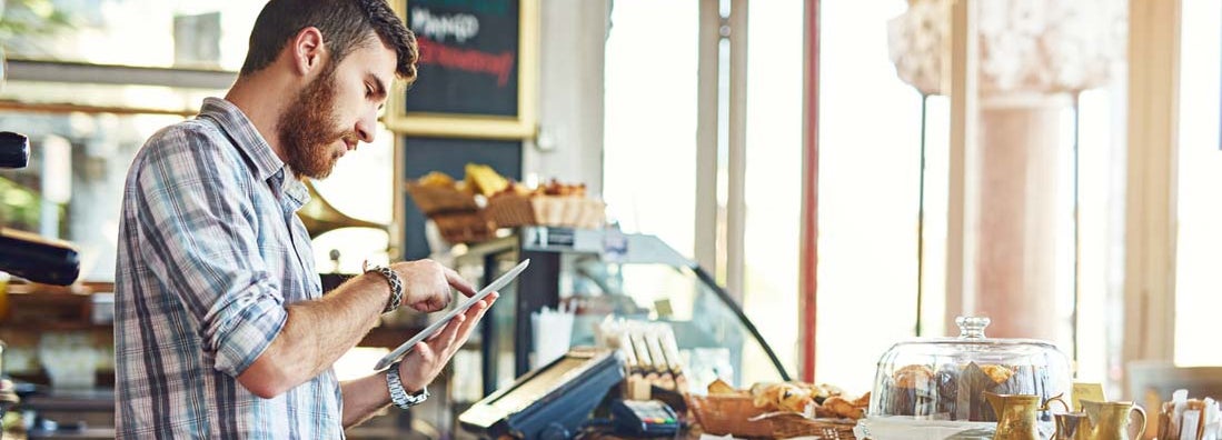 Man researching franchise restaurant insurance while working in a coffee shop