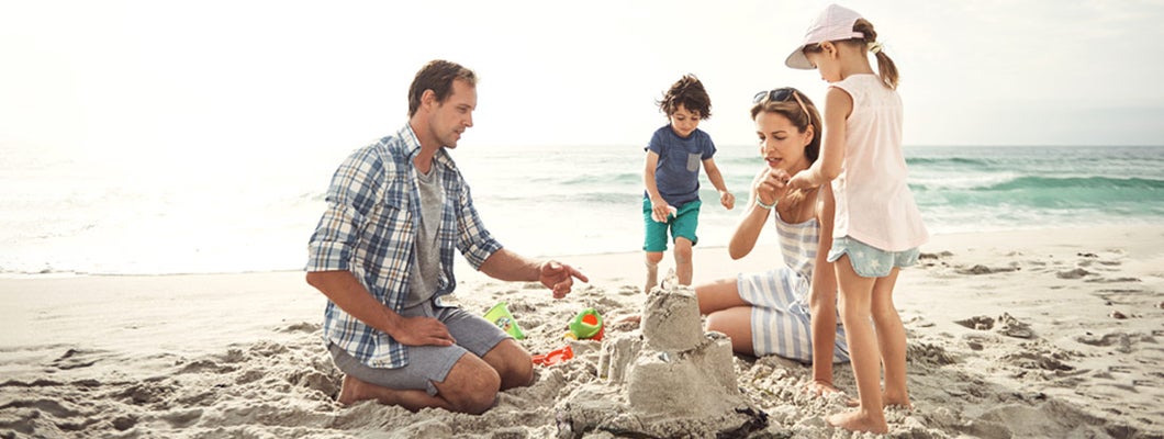 Family with young children building a sandcastle together on the beach