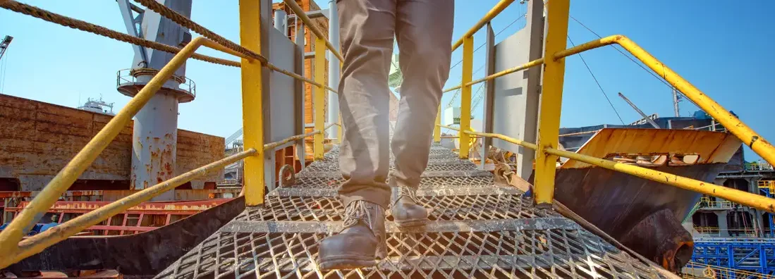 Engineer walking on the steel bridge cross over at workplace. Find Best Companies Workers' Compensation.