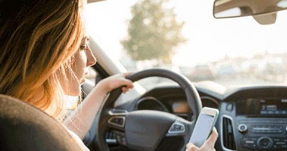 Teen looking to her smartphone while driving car