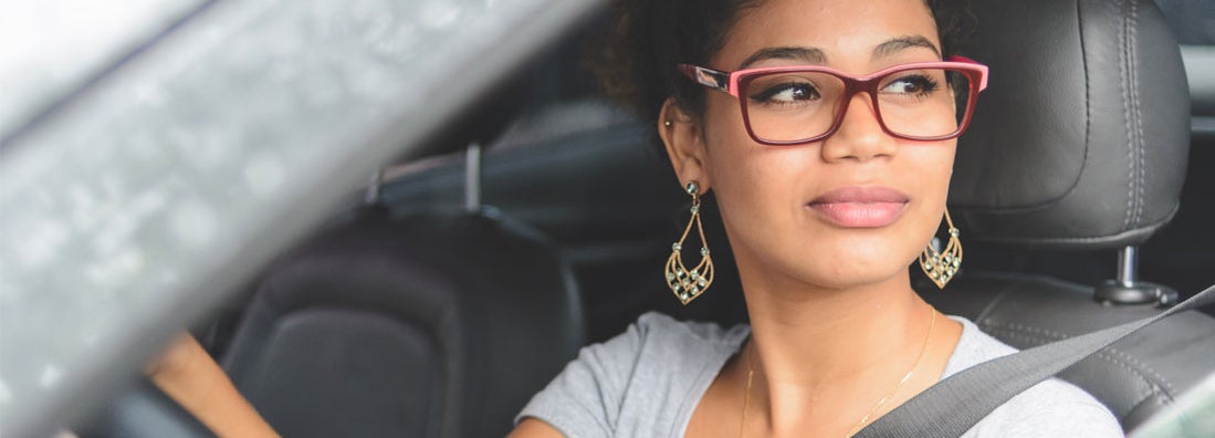 Portrait of young woman driving a car. Find College Student Car Insurance.