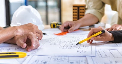 Architect checks construction blueprints on new project with tools at desk in office.