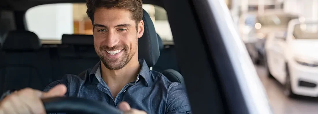 Man examining a new car in a showroom. How to Find the Best Car Insurance in Essex, Vermont.