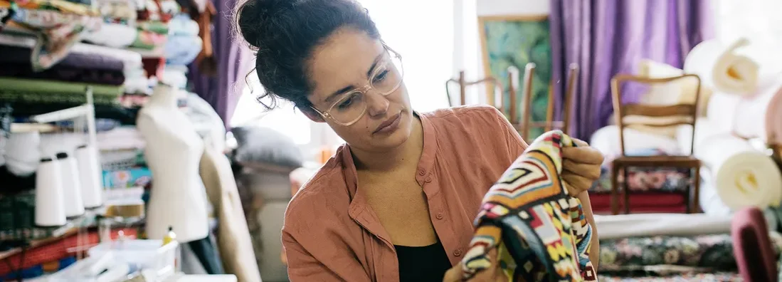 Craftswoman Examining Colorful Fabric In Workshop. Chesterfield, Missouri Business Insurance. 