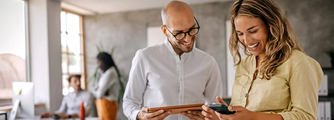 Businessman and businesswoman smiling looking at phone. Find Georgia Landlord Insurance.