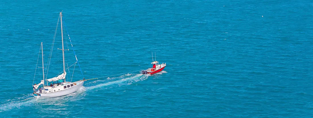 Sailboat Being Towed to the Dock. Does Boat Insurance Cover Towing?