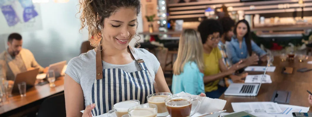 Waitress holding a tray with coffee for customers in background. Find Public Liability Insurance.