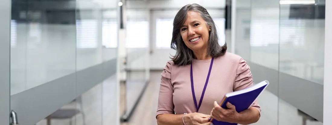 Happy teacher smiling at the university. Find Teacher Car Insurance Discounts.