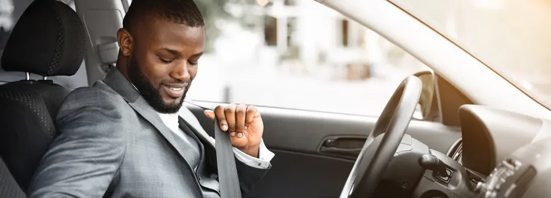 Businessman fastening seat belt in his car. Find Irvine, California car insurance.