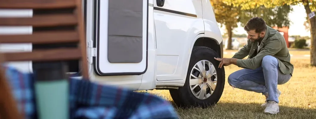 Man checking a tire on a recreational vehicle. RV Insurance Claims. 