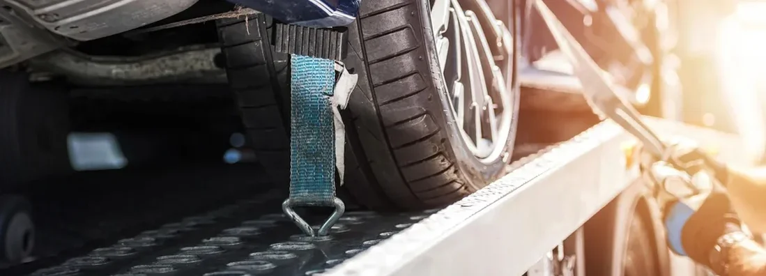 Towing operator managing vehicle on flatbed truck. What Is Towing and Roadside Assistance Coverage?