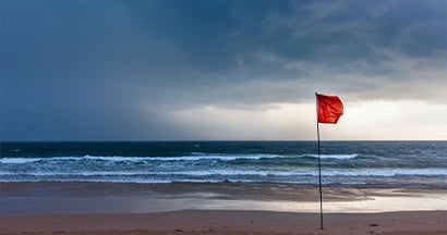 Storm warning flags on beach. Hurricane preparation guide.