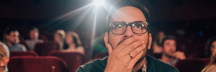 Young man watching a superhero movie at the cinema