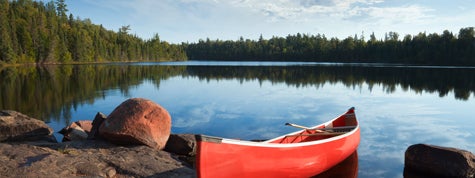 A red canoe rests on a rocky shore in the Boundary Waters of Minnesota