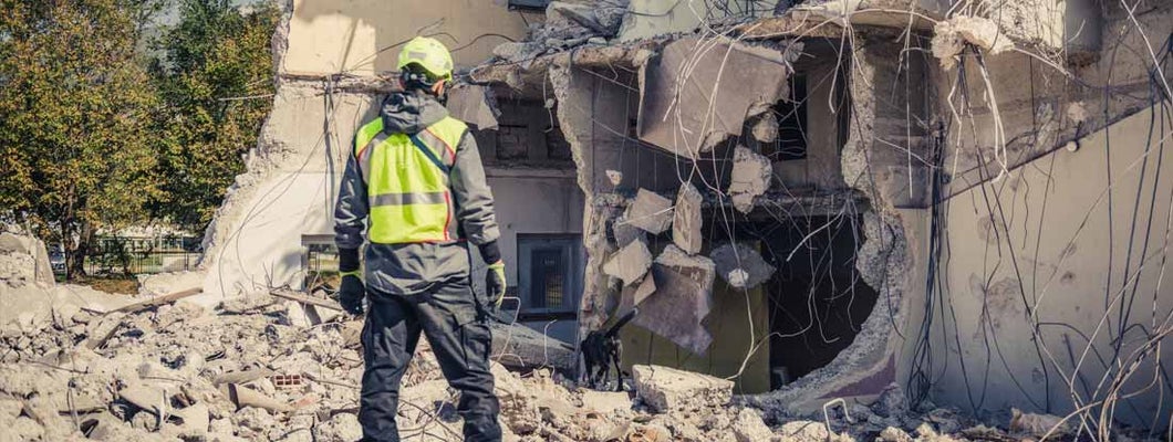 Rescuer search home ruins with help of rescue dog. Find Earthquake Safety Tips: How to Be Prepared in Case of Earthquakes.