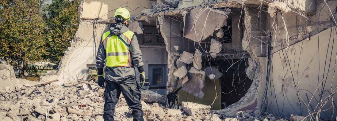 Rescuer search home ruins with help of rescue dog. Find Earthquake Safety Tips: How to Be Prepared in Case of Earthquakes.