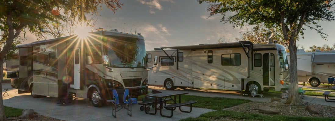 Motorhomes/RV's parked with a beautiful sunburst above the roof. Find Nebraska RV Insurance.