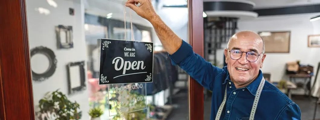 Man hanging an opening sign at men's clothing store. Find Franklin, Tennessee business insurance.