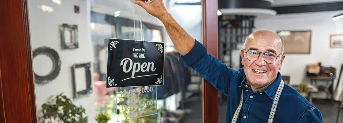 Man hanging an opening sign at men's clothing store. Find Franklin, Tennessee business insurance.