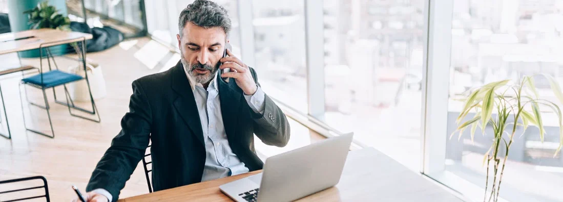 Businessman at the office talking on cell phone. Find New Jersey Errors and Omissions Insurance.