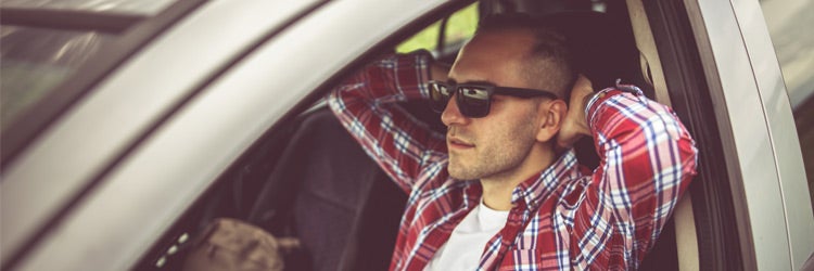 young man resting in a car outdoors