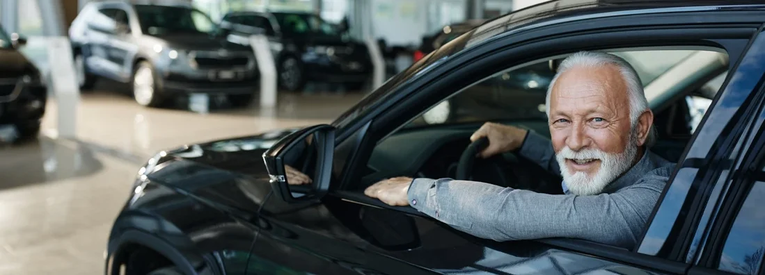 Senior man inside of a car in a showroom. How Much Car Insurance Do I Need?