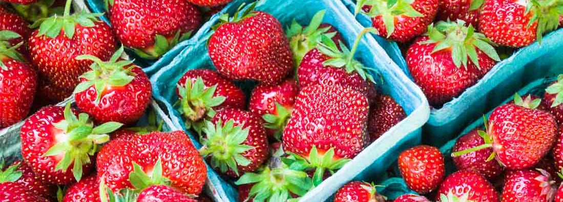 Baskets of juicy, ripe strawberries at a farmers market.