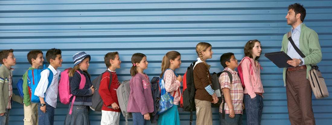 Male teacher by row of children