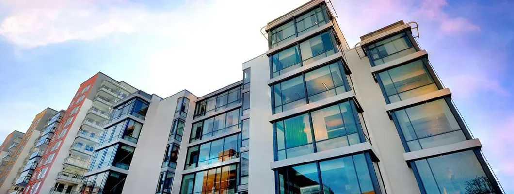 Backlit apartment building against dramatic sky. Find Alabama Condo Insurance.