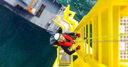 Manual high worker offshore climbing on wind-turbine on ladder. Find Workers Compensation.