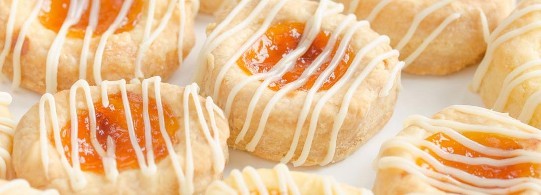 Close up of homemade cream cheese Kolache cookies filled with apricot and glazed