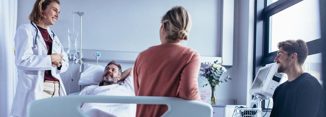 Family and friends visiting patient in hospital ward and talking with doctor. Find Long Term Disability Insurance.