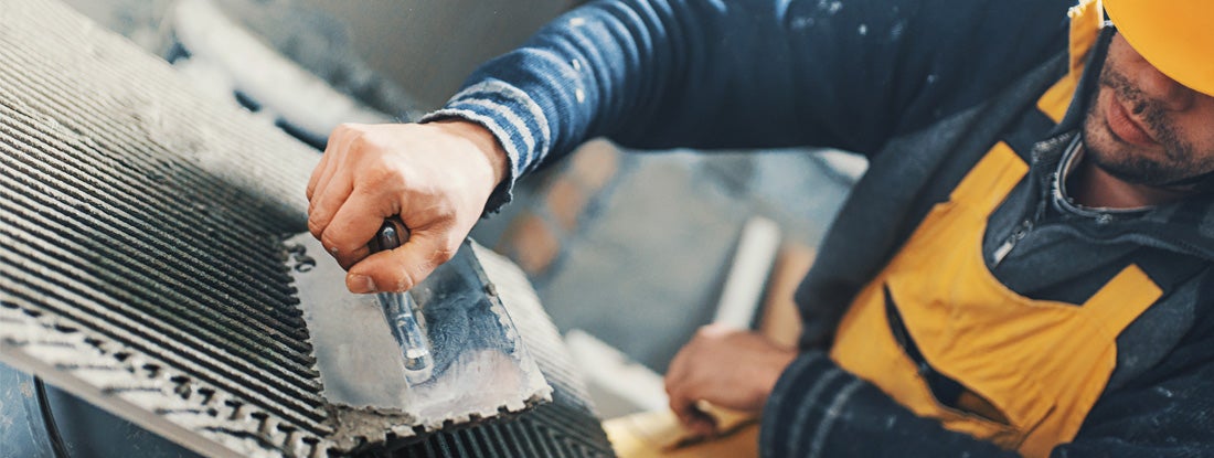 Tile contractor applying adhesive on a tile