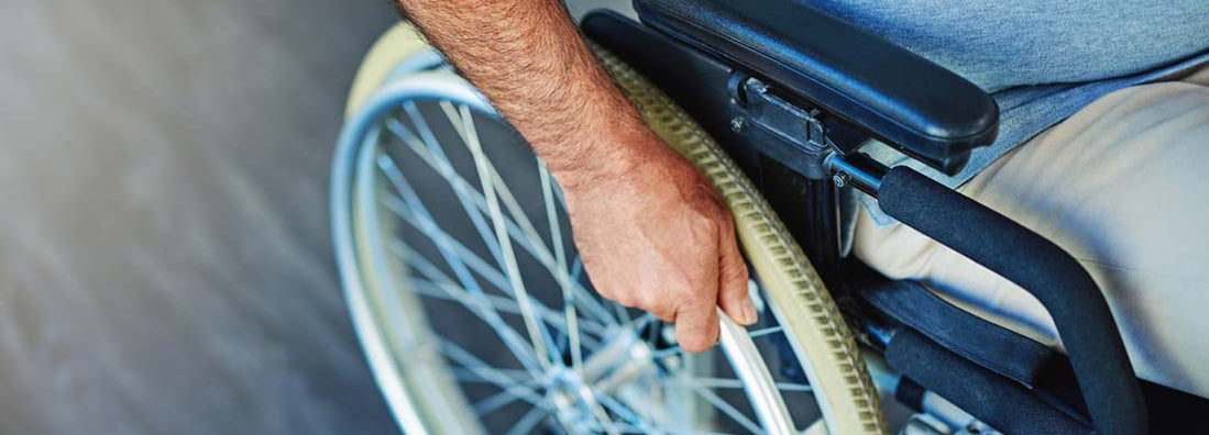 Closeup shot of an unrecognizable man sitting in a wheelchair. Find supplemental disability insurance.