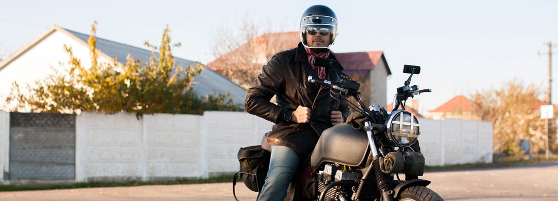 Man and old custom cafe-racer Motorcycle on forest at sunset. Find Louisiana motorcycle insurance.