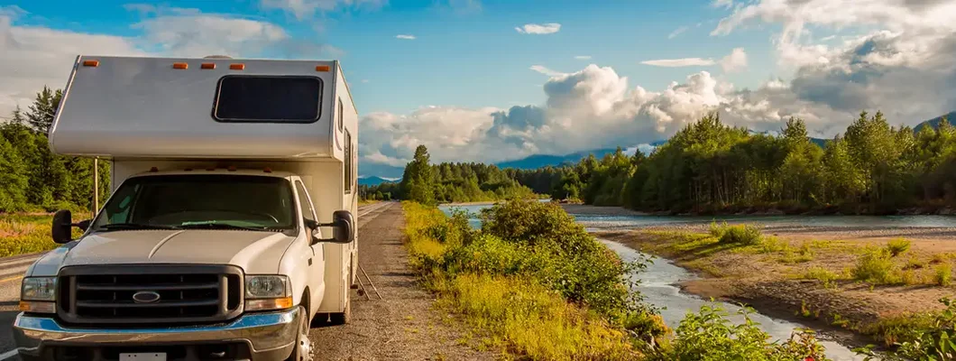 Camper parked beside river in the evening sun. Find South Carolina RV Insurance.